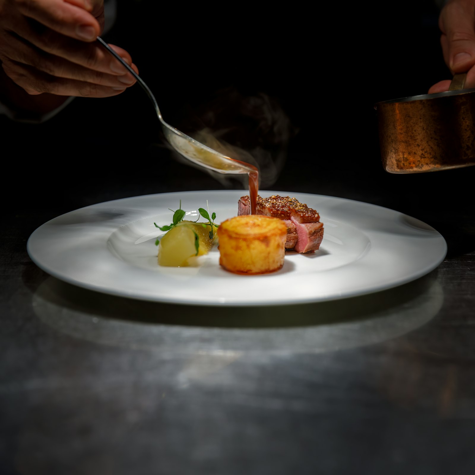 Chef plating a fine dining dish with sauce